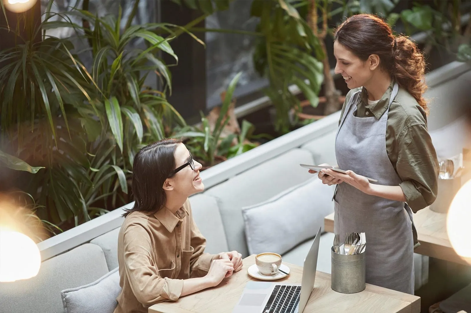 A cafe server chatting with a smiling customer